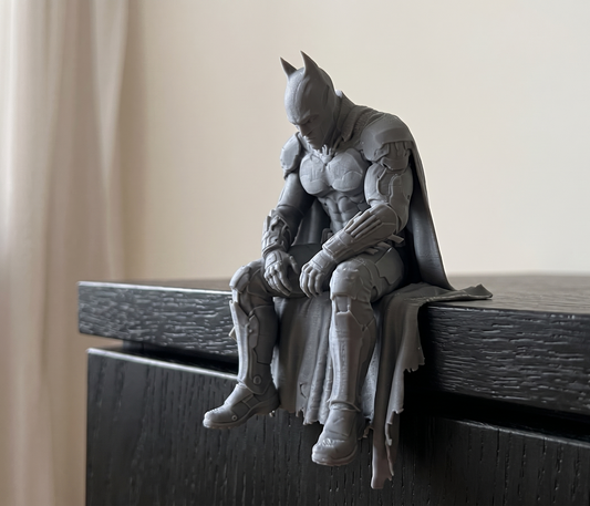 Batman figurine sitting on a ledge with cape draped